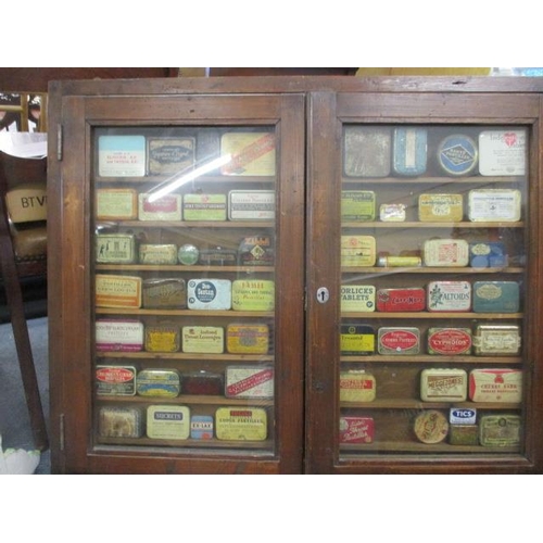 290 - A collection of small collectable tins, mainly health related, contained in a stained pine, twin gla... 