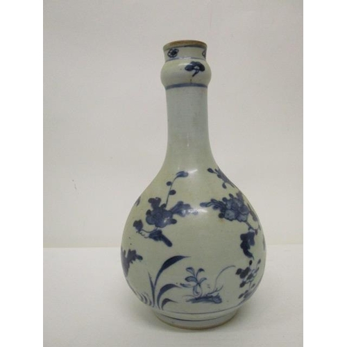 171 - An 18th century provincial Chinese bottle vase decorated with a flowering tree and plants, in blue o... 