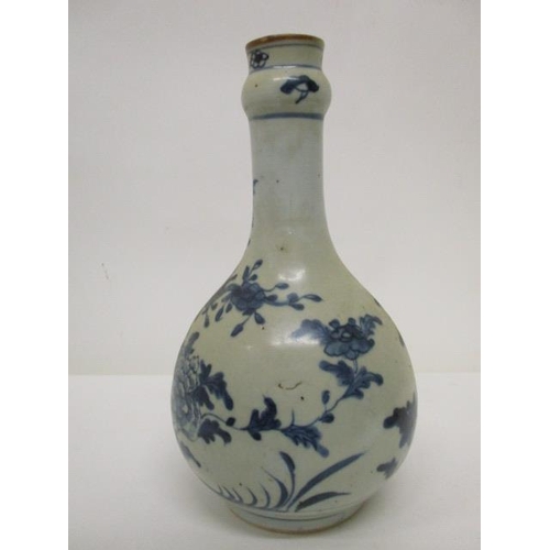 171 - An 18th century provincial Chinese bottle vase decorated with a flowering tree and plants, in blue o... 