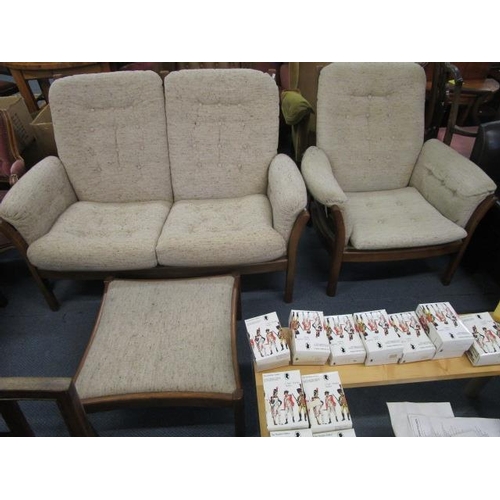 7 - An Ercol three-piece lounge suite comprising a two-seater sofa, a matching armchair and stool, with ... 