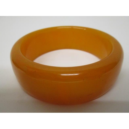 174 - Two Bakelite bangles, one egg yolk coloured and the other a pale brown, 125g