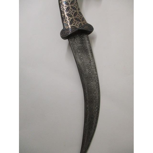 66 - An Indian Niello white metal dagger with a Damascus curved blade, rams head pommel and Niello sheath... 