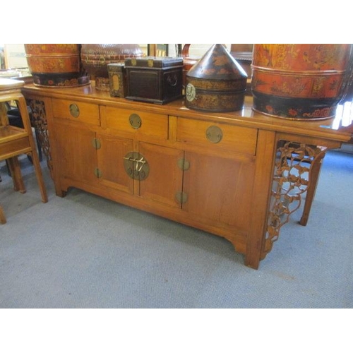 244 - A Chinese oak scroll desk with three short drawers and cupboards below flanked by pierced floral bra... 