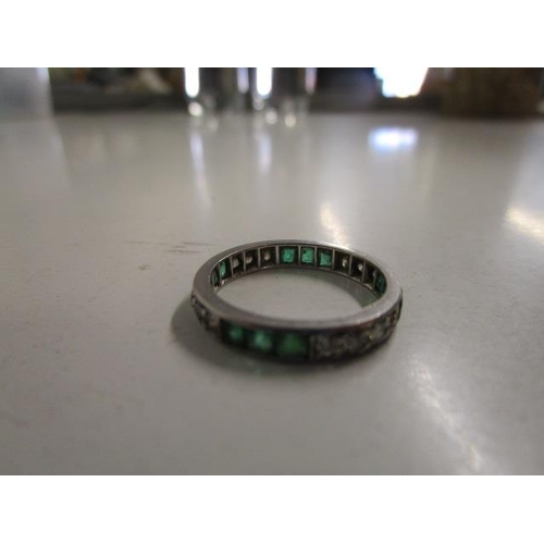 312 - A white metal diamond and emerald full eternity ring, weight 2.9g