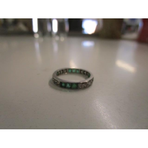 312 - A white metal diamond and emerald full eternity ring, weight 2.9g