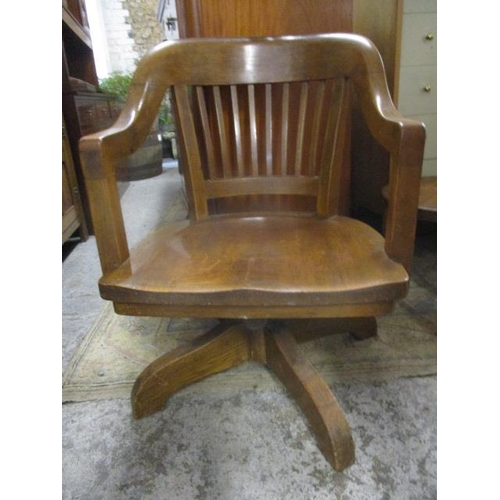 361 - An early 20th century oak desk chair with a spindle back on splayed legs