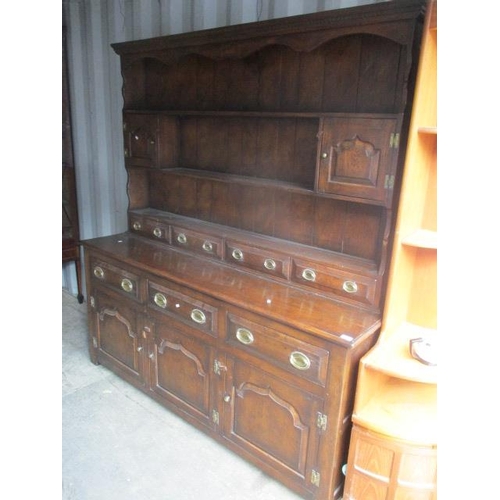 140 - A modern Georgian style oak dresser having a plate rack with a dentil moulded cornice above panelled... 