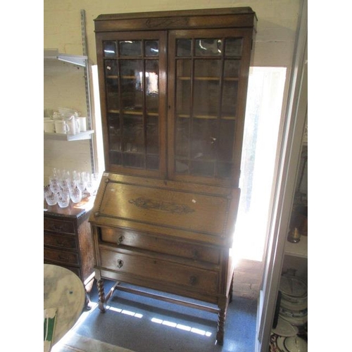 184 - A 1930s oak bureau bookcase having twin glazed doors above a fall flap and two long drawers, 76 1/2