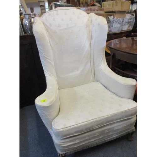 170 - An early 20th century wing back armchair with loose cream cover depicting embroidered bees