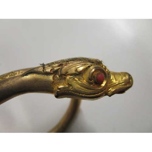 251 - A late Victorian/Edwardian gilt metal snake bangle set with coral eyes and a coral pearl in its mout... 