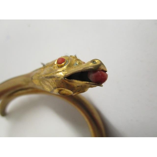 251 - A late Victorian/Edwardian gilt metal snake bangle set with coral eyes and a coral pearl in its mout... 