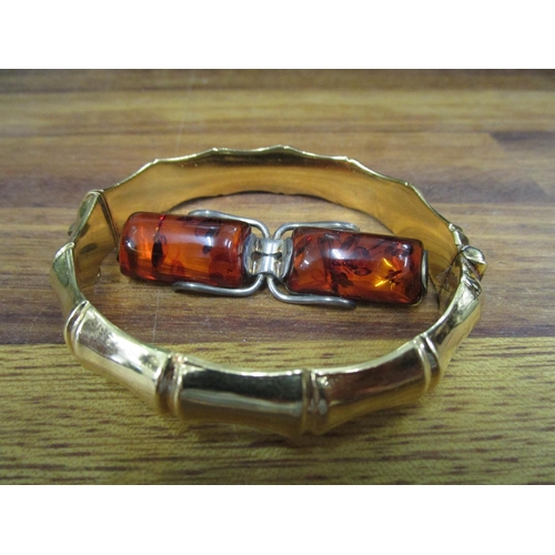 69 - A rolled gold bracelet and a silver and amber brooch