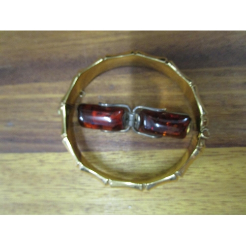 69 - A rolled gold bracelet and a silver and amber brooch