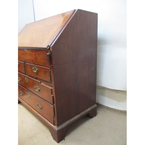 366 - An early 18th century walnut bureau with a feather and crossbanded fall flap enclosing a well, pigeo... 