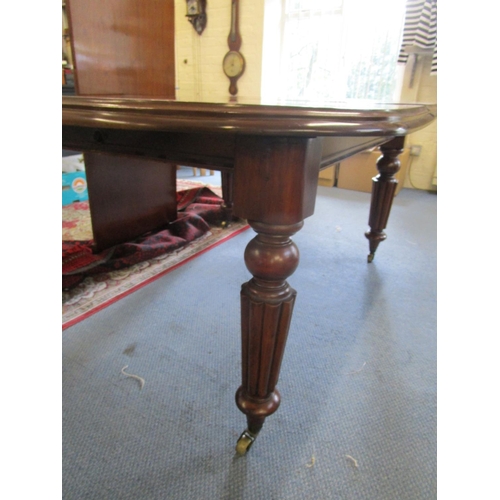 130 - A Victorian mahogany wind-out dining table on turned legs and castors, with one extra leaf 28