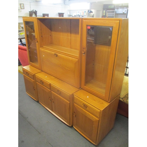 73 - An Ercol blonde elm, three section bookcase cabinet having glazed doors flanking a fall flap above d... 