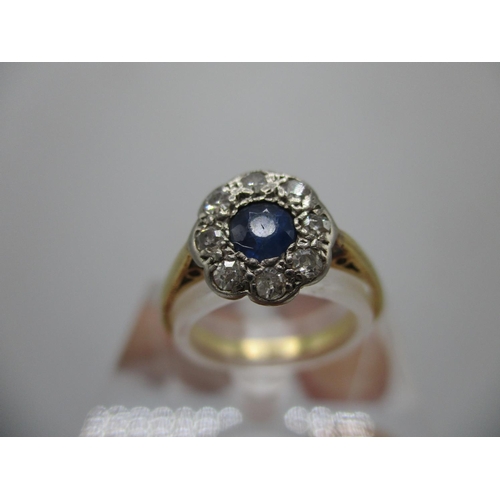 240 - A gold and platinum coloured ring set with a central blue sapphire, set within a band of eight diamo... 