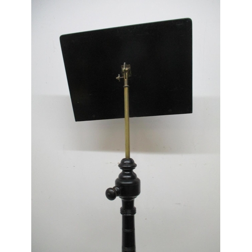 228 - A Victorian ebonized music stand with an angle adjustable panel over a height adjustable brass colum... 