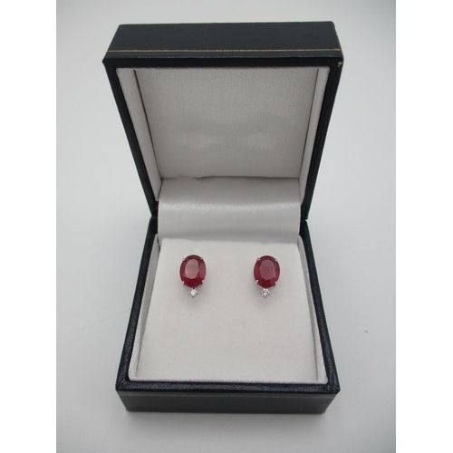 260 - A pair of platinum stud earrings, each set with a treated ruby and a diamond below, rubies 4ct total... 