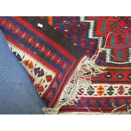 202 - An Iranian hand woven rug in red, blue, green, white and black colours with tasselled ends, 300 x150... 