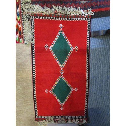 202 - An Iranian hand woven rug in red, blue, green, white and black colours with tasselled ends, 300 x150... 