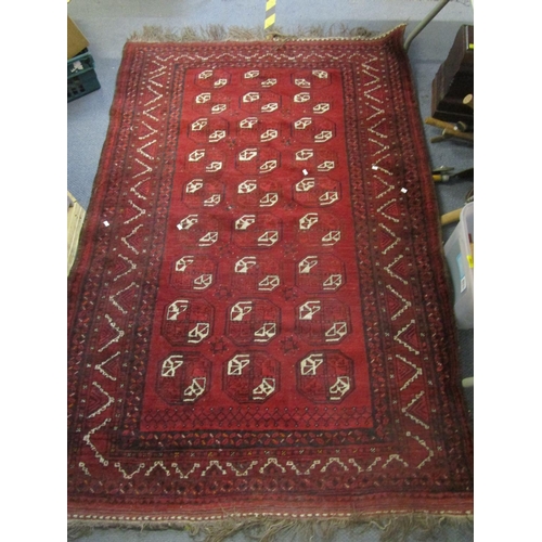 43 - A Pakistan hand woven red ground rug decorated with three rows of nine elephant gulls, multi guard b... 