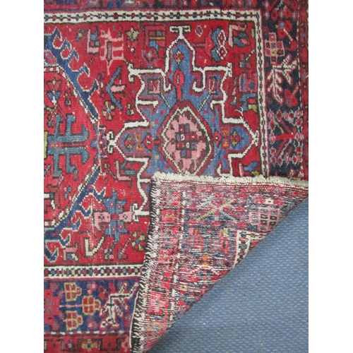 43 - A Pakistan hand woven red ground rug decorated with three rows of nine elephant gulls, multi guard b... 