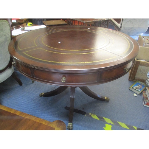 91 - A reproduction Regency inspired mahogany drum table having a leather top, fluted column and four spl... 