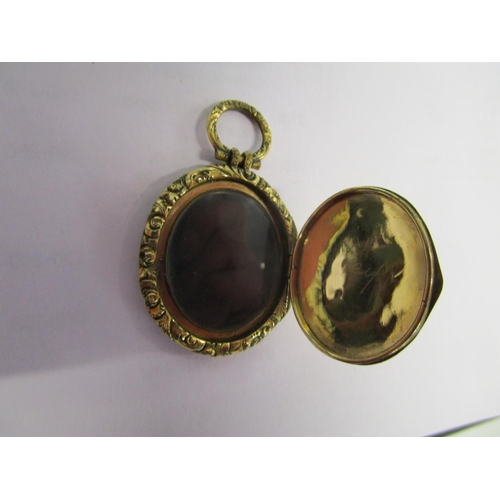 311 - A Victorian/Edwardian gold coloured pendant locket with floral engraved decoration, on a yellow meta... 