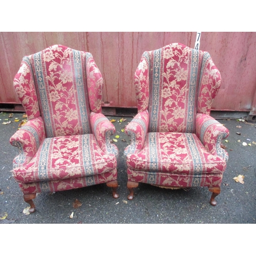 147 - A pair of late 20th century wing back upholstered armchairs, upholstered in a floral red fabric with... 