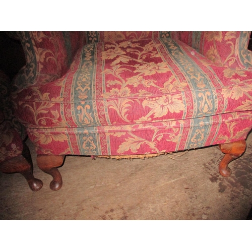 147 - A pair of late 20th century wing back upholstered armchairs, upholstered in a floral red fabric with... 