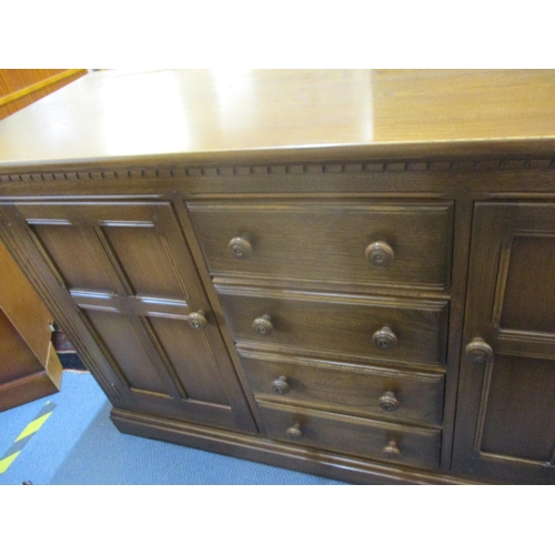 316 - An Ercol dresser base with four central short drawers flaked by fielded cupboards