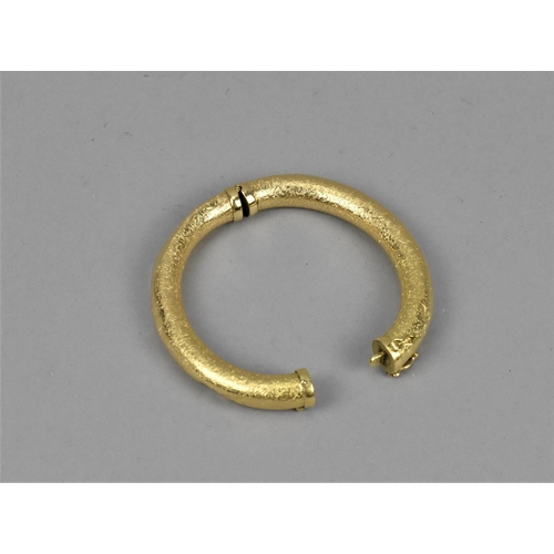 44 - An 18ct yellow gold bangle, of hollow round section with textured design and box clasp, inner diamet... 