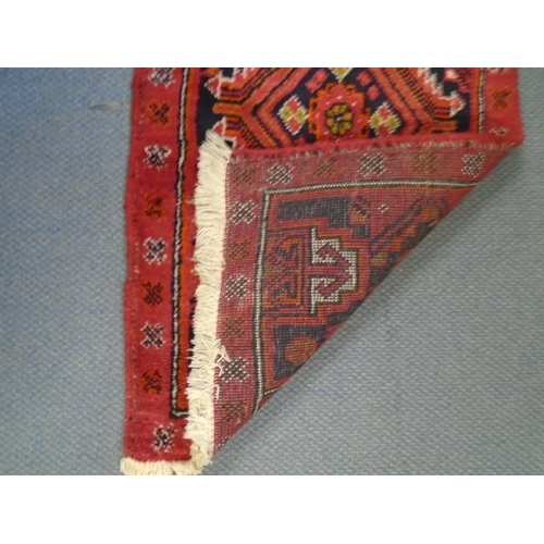 75 - A small handwoven Middle Eastern runner, red ground with a line of four elephant gulls, geometric an... 