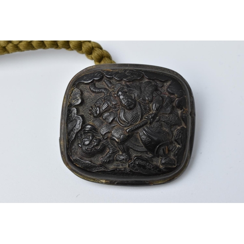 26 - A Japanese pressed horn Manju, 19th century, of rectangular form with carved samurai and tiger to on... 