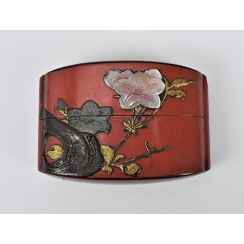 14 - A Japanese Meiji period red lacquer two case inro, decorated with relief flowers to one side and mac... 