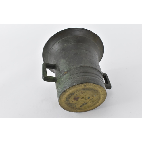 198 - An 18th century or earlier Middle Eastern bronze mortar and pestle, modelled with flanged decoration... 