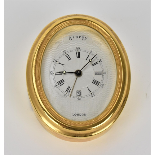 67 - An Asprey gilt brass alarm desk clock, having a machine turned dial, Roman numerals, luminous marker... 