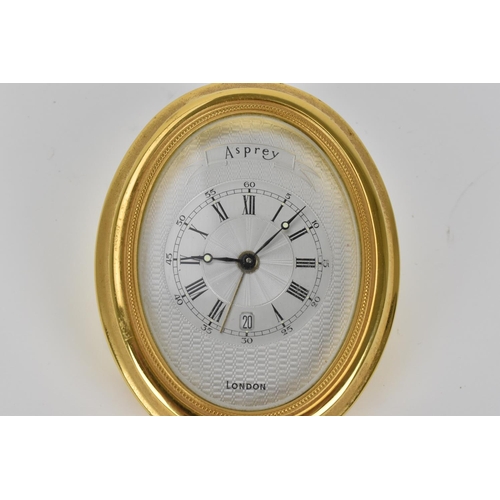 67 - An Asprey gilt brass alarm desk clock, having a machine turned dial, Roman numerals, luminous marker... 