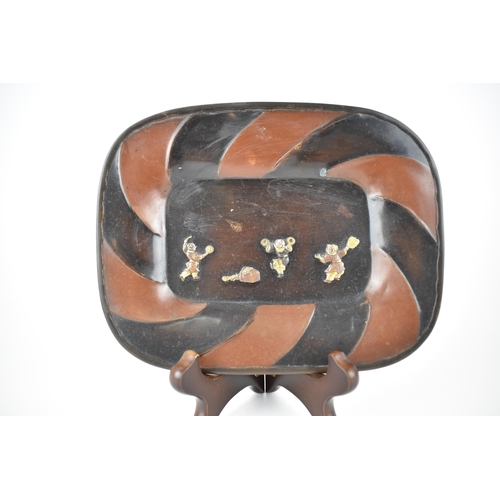 126 - A Japanese Meiji/Taisho period patinated copper dish with a scroll design border and three dancing f... 