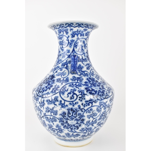 135 - A Chinese late Qing dynasty blue and white hu vase with twin bamboo handles, decorated with entwined... 