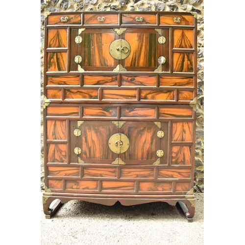 148 - A Korean 19th century two part Tansu cabinet, with brass brackets and handles, with a figured veneer... 