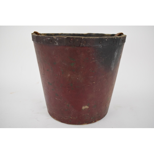 172 - A 19th century painted papermache fire bucket with an armorial device, a leather carrying handle and... 