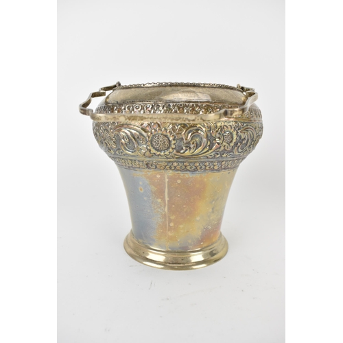 228 - An Indian silver ice bucket with a swing handle, a bulbous upper section and tapered sides, embossed... 