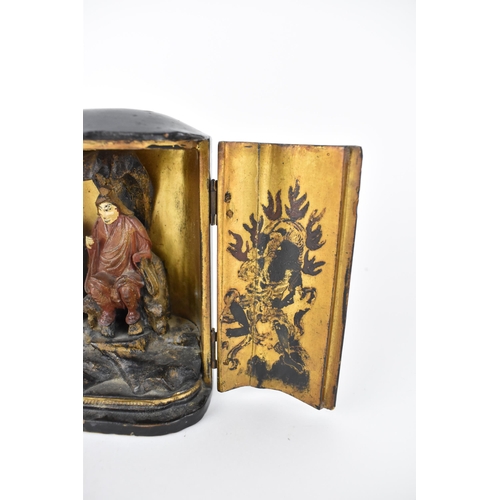 71 - A Chinese lacquered travelling shrine, with a deity seated on rockwork to the interior, with designs... 