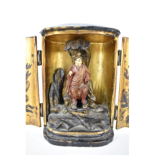 71 - A Chinese lacquered travelling shrine, with a deity seated on rockwork to the interior, with designs... 