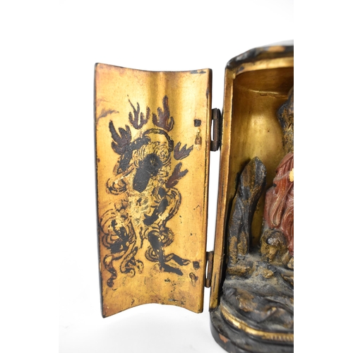 71 - A Chinese lacquered travelling shrine, with a deity seated on rockwork to the interior, with designs... 