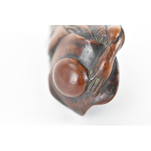 73 - A Japanese Edo period (18th/19th century) wooden netsuke of a scholar holding his hat on, 9.5cm h