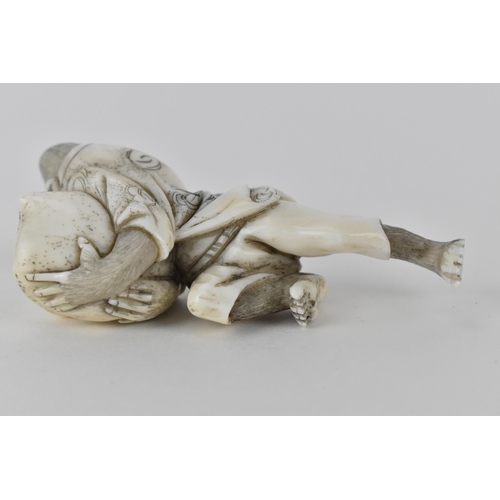 78 - A Japanese Meiji period early 20th century ivory netsuke of a monkey wearing a nappy and clutching a... 