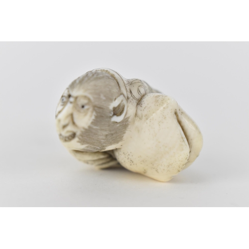 78 - A Japanese Meiji period early 20th century ivory netsuke of a monkey wearing a nappy and clutching a... 